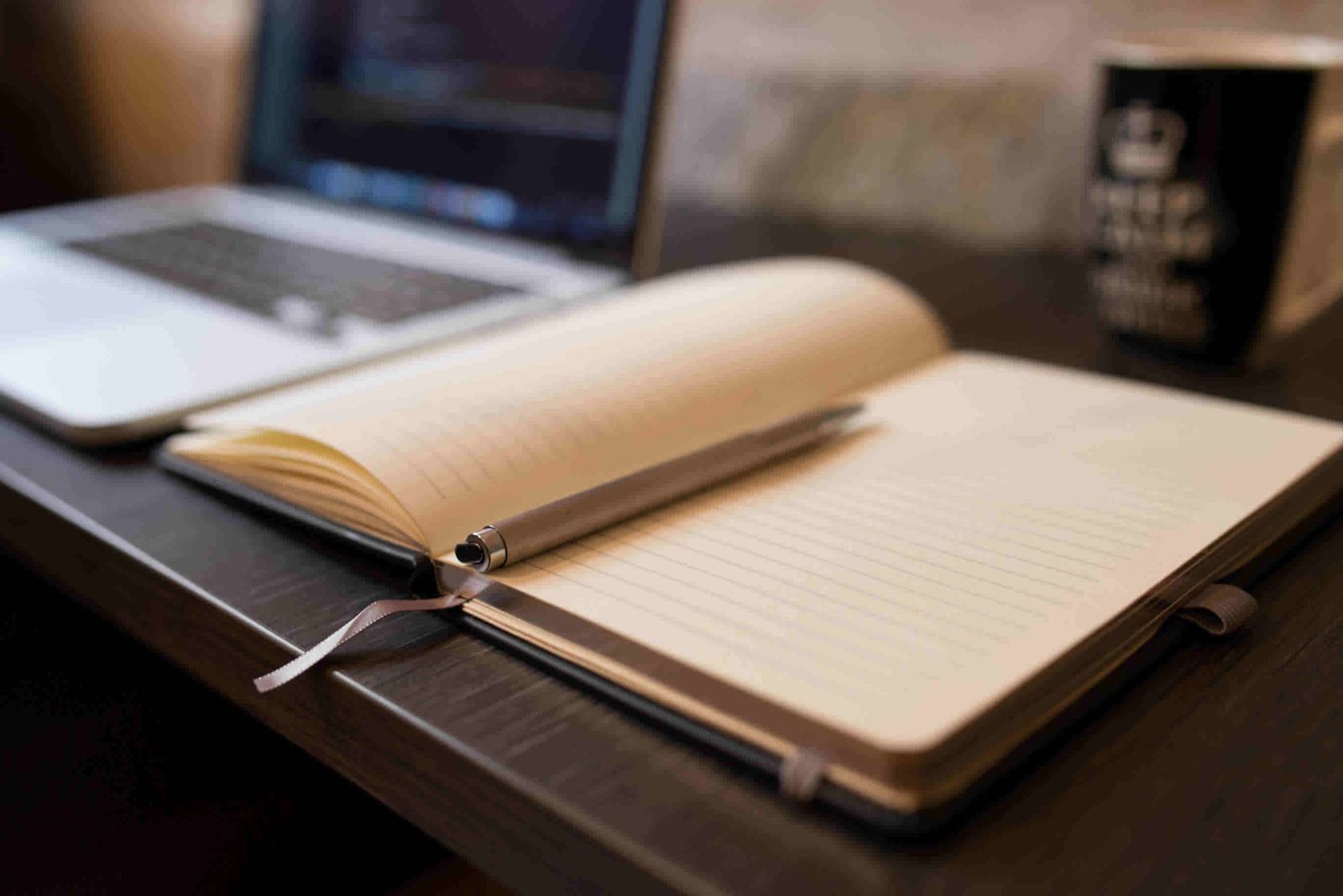 Caderno aberto com caneta sobre uma mesa de escritório, representando a organização documental de um inventário
