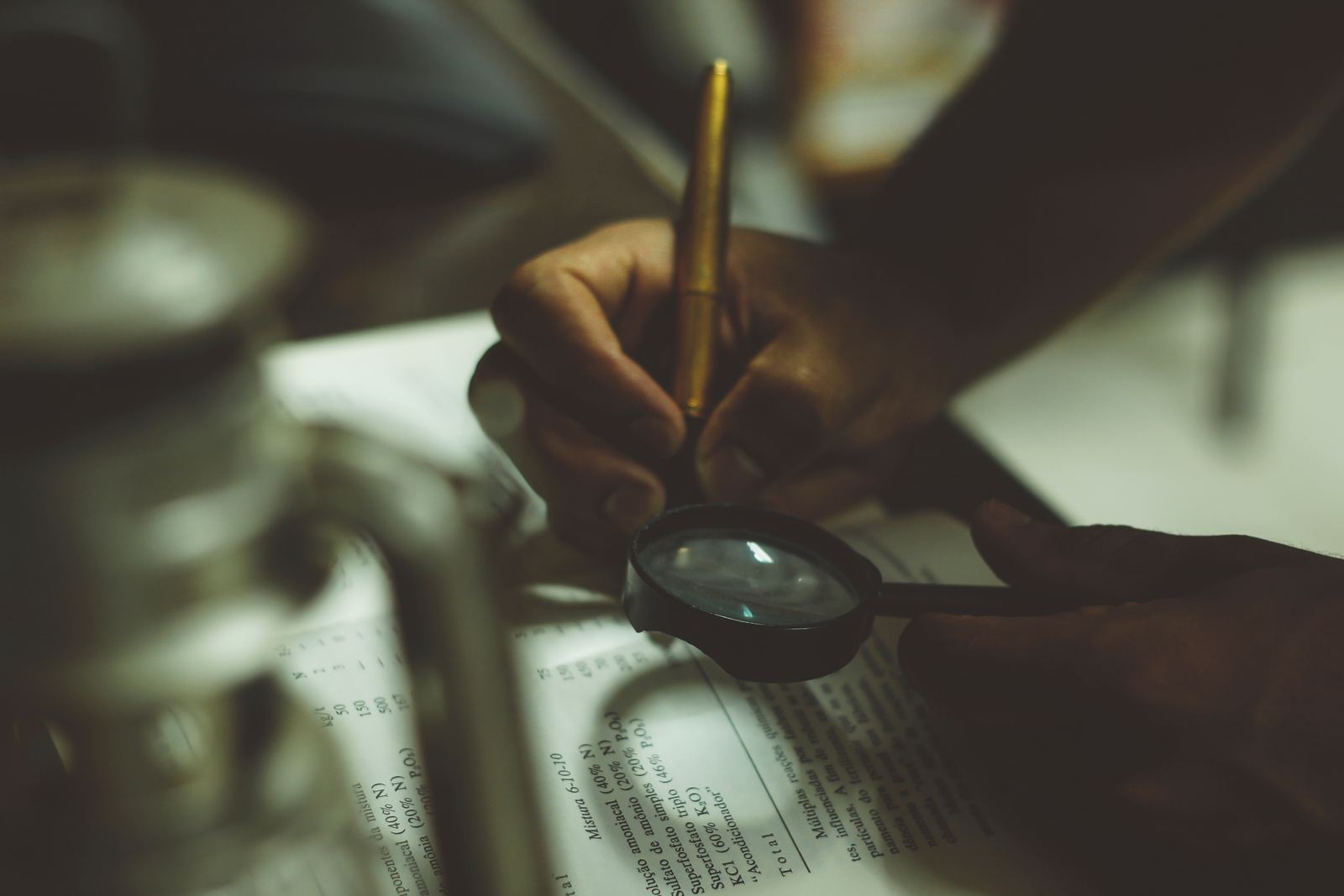 Mãos segurando uma lupa sobre um documento, representando a análise jurídica do caso